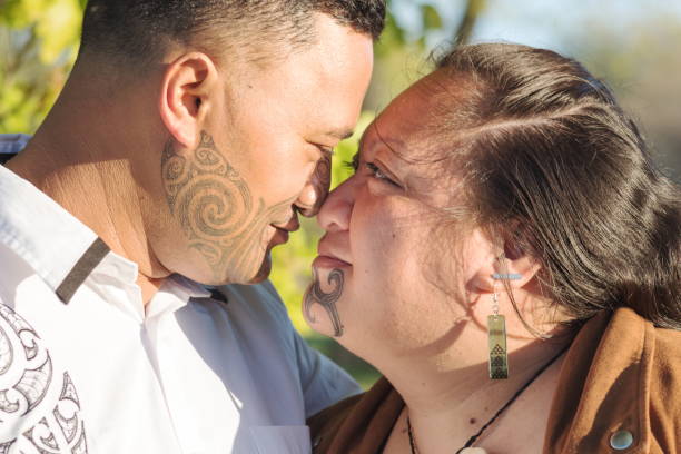 Portrait of an attractive young Maori couple staring into each others eyes taken outdoors stock photo