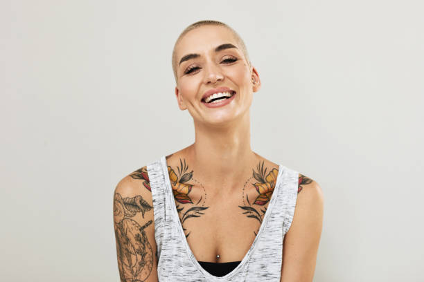 Portrait of an attractive young woman displaying her tattoos  against a grey background stock photo