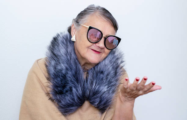 Portrait of an elderly woman with glasses. An old hipster lady with a fur collar and sunglasses. Older people, the concept of fashion. A fashionable hipster woman poses for the camera stock photo