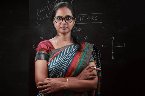 Portrait of an Indian lady teacher Portrait of an Indian lady teacher stands in front of a blackboard chalkboard visual aid photos stock pictures, royalty-free photos & images