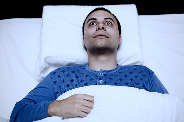 portrait of an insomniac man trying to sleep - breed stockfoto's en -beelden