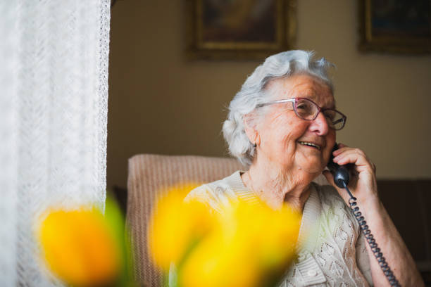 portret van een oudere vrouw die met de telefoon praat - seniore vrouwen stockfoto's en -beelden