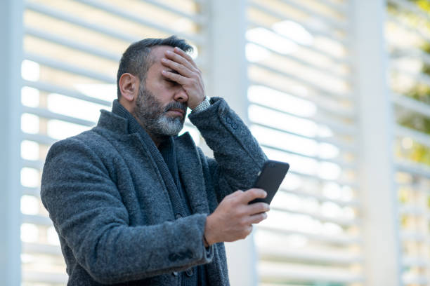 Portrait of an upset man looking at his mobile phone stock photo