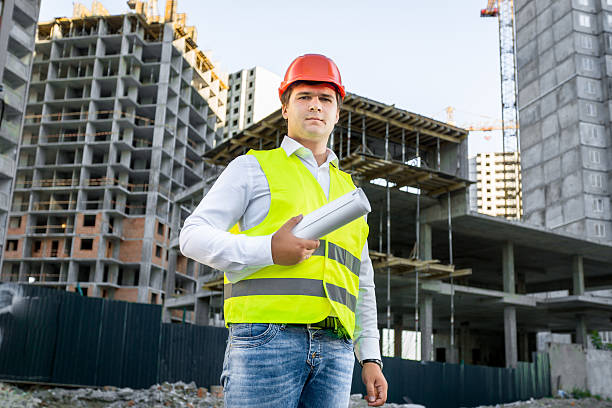 Portrait of architect in red hardhat posing on building site