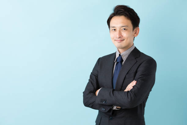 portret van aziatische zakenman geïsoleerd op blauwe achtergrond - japanse etniciteit stockfoto's en -beelden
