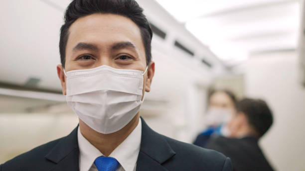 porträtt av asiatiska manliga steward bär medicinsk ansiktsmask för att förhindra coronavirus på flygplanshytt. flygbolag affärsansvar service och stöd resor under virus epidemi - halvbild bildbanksfoton och bilder