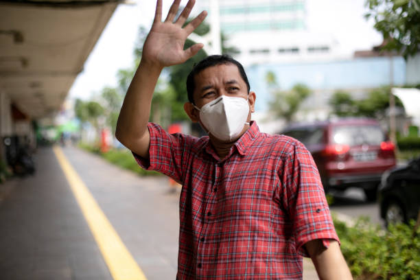Portrait of asian man adult wearing mask on the street Portrait of asian adult wearing mask and waving goodbye for his friend wave goodbye asian stock pictures, royalty-free photos & images