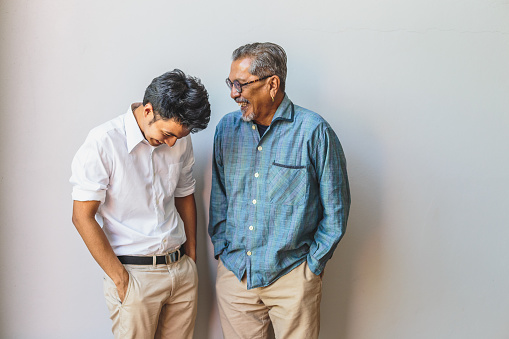 Portrait of Asian senior father and his adult son having fun together and standing on gray backgrounds