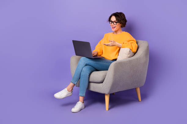 Portrait of attractive cheerful girl sitting using netbook calling on web communicating isolated over violet lilac color background stock photo