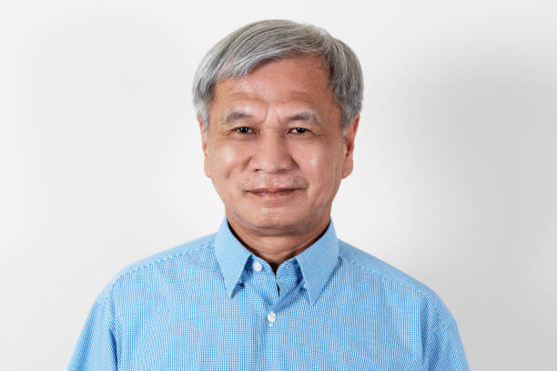 portrait of attractive senior asian man smiling and looking at camera in studio with white isolated background feeling positive grandpa. headshot of mature older chinese man or father concept. - medial object imagens e fotografias de stock