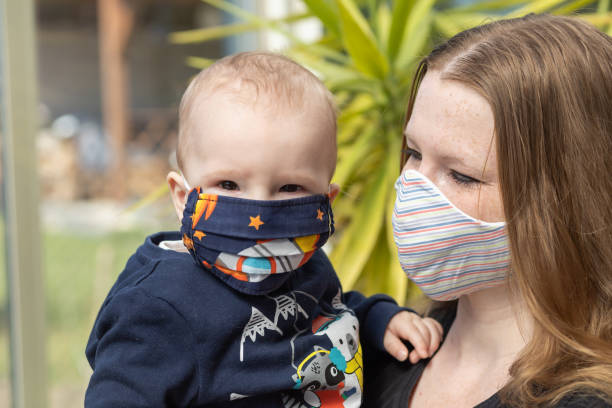 Portrait of baby and mother together with reusable protective face mask stock photo