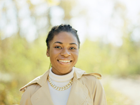 Young beautiful black woman looking at camera on the background of autumn landscape