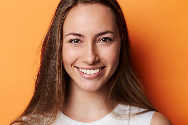 Portrait of beautiful brunette in orange studio Portrait of beautiful brunette in orange studio brown eyes stock pictures, royalty-free photos & images