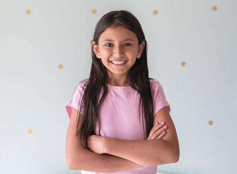 Portrait of beautiful latin american little girl facing camera smiling very happy with arms crossed