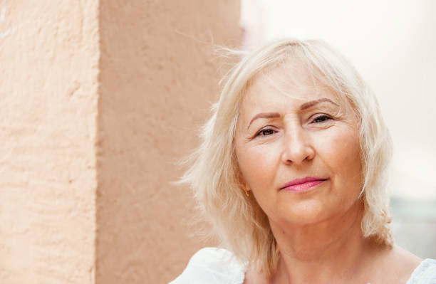Portrait of beautiful senior woman with white hair standing by wall. stock photo