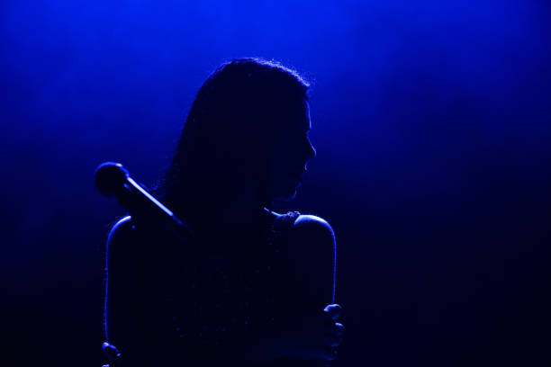 Portrait of beautiful singing woman on dark background. stock photo