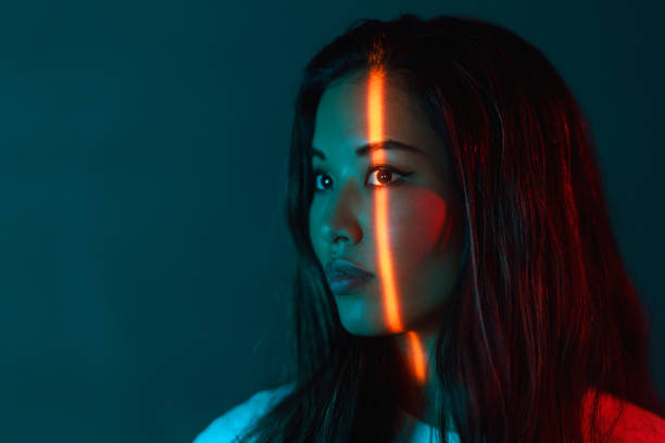 Portrait of beautiful woman lit by neon colored lights stock photo