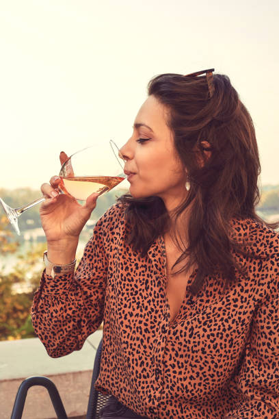 Portrait of beautiful woman using cellphone and drinking wine outdoors. stock photo