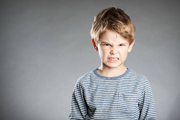 Portrait of boy, emotion, angry, grey background stock photo