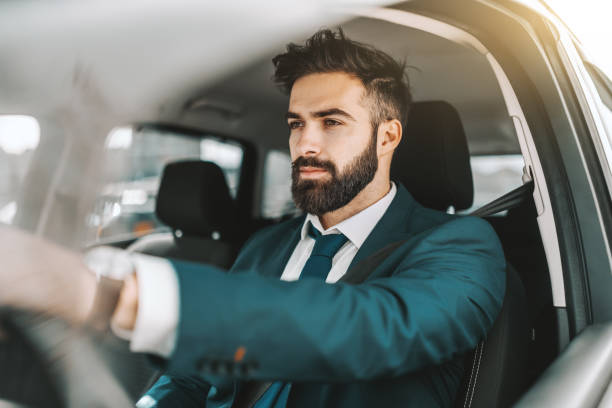 Portrait of caucasian bearded businessman in formal wear driving car.  man driving suit stock pictures, royalty-free photos & images