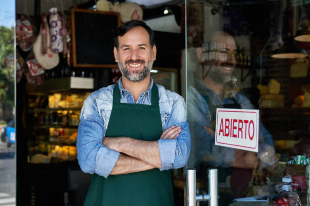 Portrait of Cheerful Male Shopkeeper Standing at Front Door stock photo