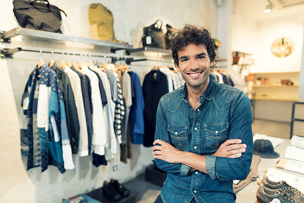 portrait of cheerful owner in clothing store. looking at camera - verkoop kleding stockfoto's en -beelden