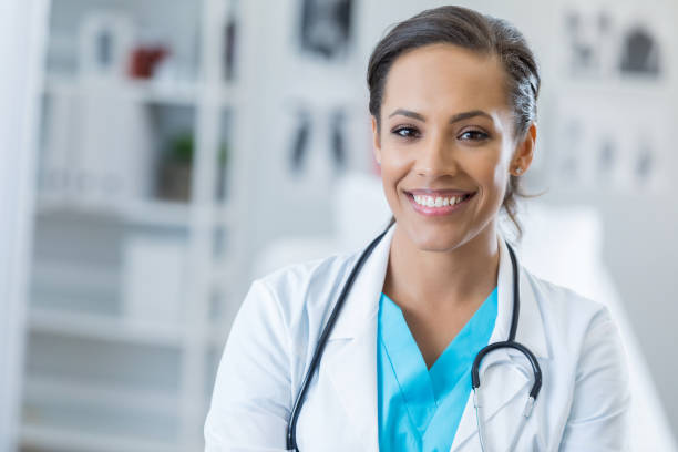 Portrait of confident female healthcare professional Pretty mid adult African American surgeon smiles cheerfully at the camera. She is wearing a stethoscope and lab coat. lab coat stock pictures, royalty-free photos & images