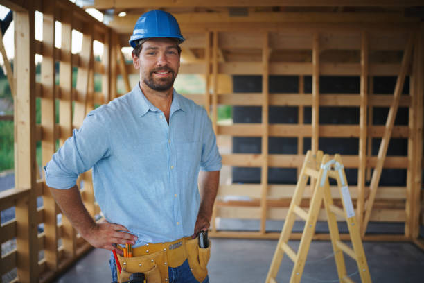 Portrait of construction worker smiling and looking at camera, diy eco-friendly homes concept. stock photo