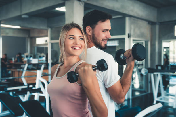 Portrait of Couple Love in Fitness Training With Dumbbell Equipment., Young Couple Caucasian are Working Out and Training Together in Gym Club., Sport and Healthy Concept. stock photo