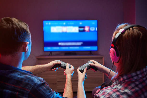 Portrait of crazy playful couple, Gamers enjoying Playing Video Games on Playstation indoors sitting on the sofa, holding Console Gamepad in hands, Xbox fans. Resting At Home, have a great Weekend stock photo