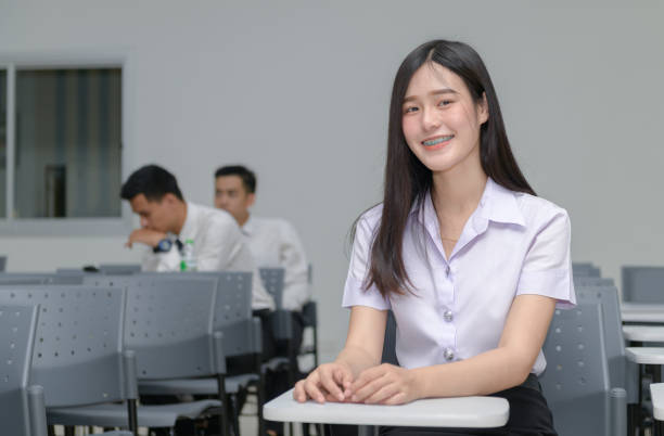 Portrait of cute asian girl student with braces on the teeth Portrait of cute asian girl student with braces on the teeth, sitting at the desk and studying at classroom university, education  concept cute thai girl stock pictures, royalty-free photos & images