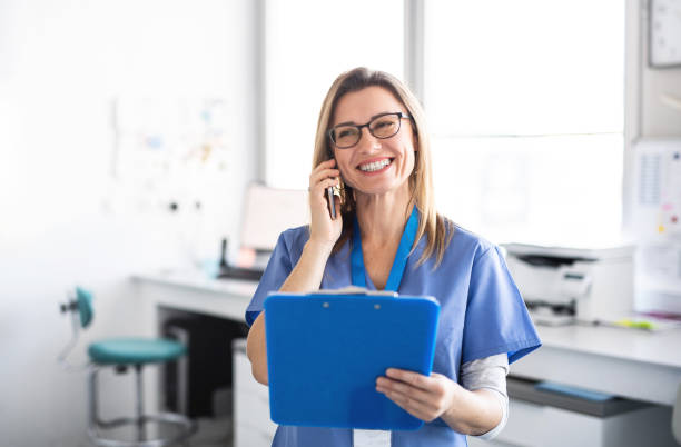 A portrait of dental assistant in modern dental surgery, using smartphone. A portrait of cheerful dental assistant in modern dental surgery, using smartphone. assistant stock pictures, royalty-free photos & images
