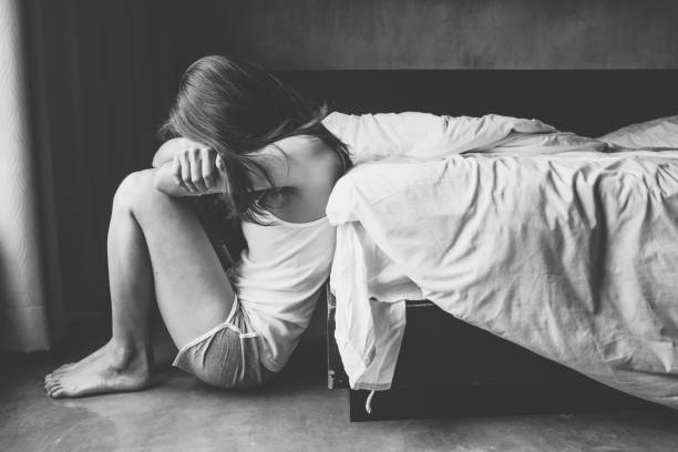 portret van depressieve vrouw alleen zittend op de vloer in de slaapkamer. - depressie verdriet stockfoto's en -beelden