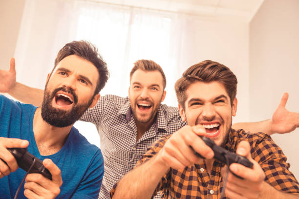 ritratto di uomini che ridono eccitati che giocano ai videogiochi - joystick soccer foto e immagini stock