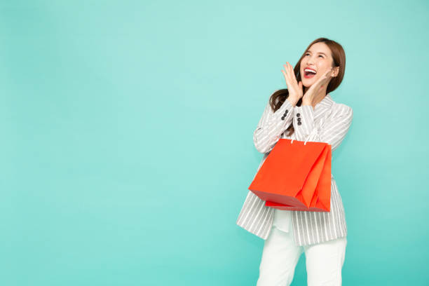 Portrait of excited screaming young asian woman holding shopping bag isolated over green background, Wow and surprised concept  tickling beautiful women pictures stock pictures, royalty-free photos & images