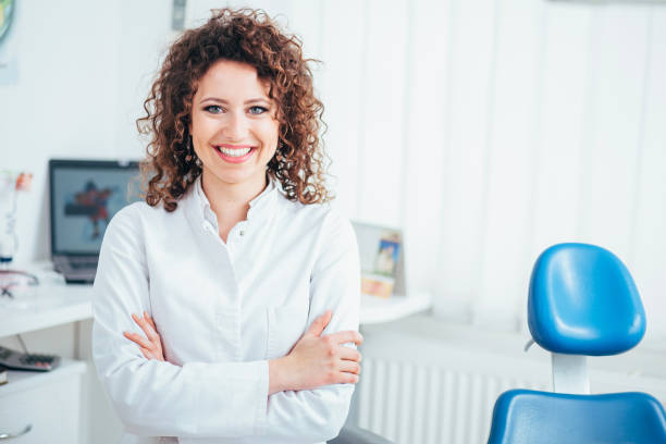 Portrait of female dentist. She standing at her office and she has beautiful smile. stock photo