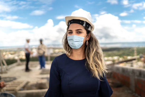 Portrait of female engineer with face mask in a construction building Portrait of female engineer with face mask in a construction building gender stereotypes stock pictures, royalty-free photos & images