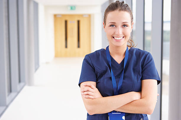 portrait of female nurse standing in hospital corridor - sjuksköterska bildbanksfoton och bilder