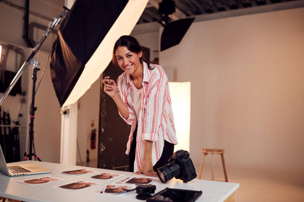 verticale du photographe féminin éditant des images de la séance photo dans le studio - photographe professionnel photos et images de collection