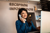istock Portrait of female receptionist at desk in hotel lobby working. 1366042492