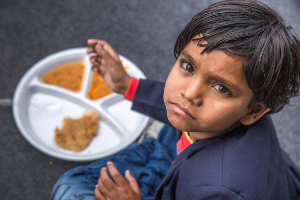 Portrait of Girl kid having mid-day meal in Indian school. Indian school children eat their free midday meal at a government school in Haryana hungry stock pictures, royalty-free photos & images