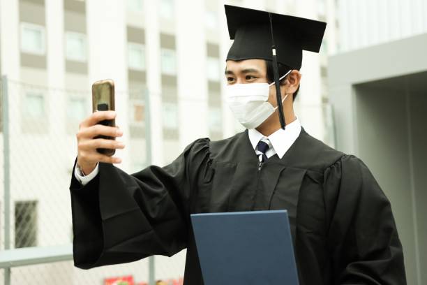 Portrait of Graduate call family and friends online Asian Young Graduate share the joy of graduation with family and friends through online calls. Video call of the graduation ceremony. online degrees stock pictures, royalty-free photos & images
