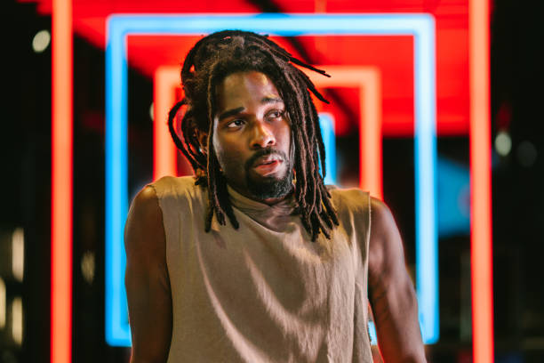porträt eines hübschen schwarzen mannes vor bunten neonlichtern - musiker stock-fotos und bilder