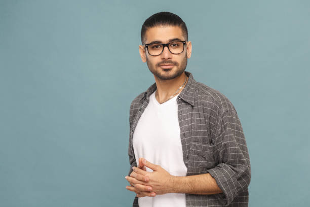Portrait of handsome man with black glasses in casual style looking at camera and smiling. Portrait of bearded handsome man with black glasses in casual style looking at camera and smiling. studio shot on blue background. young male actors stock pictures, royalty-free photos & images