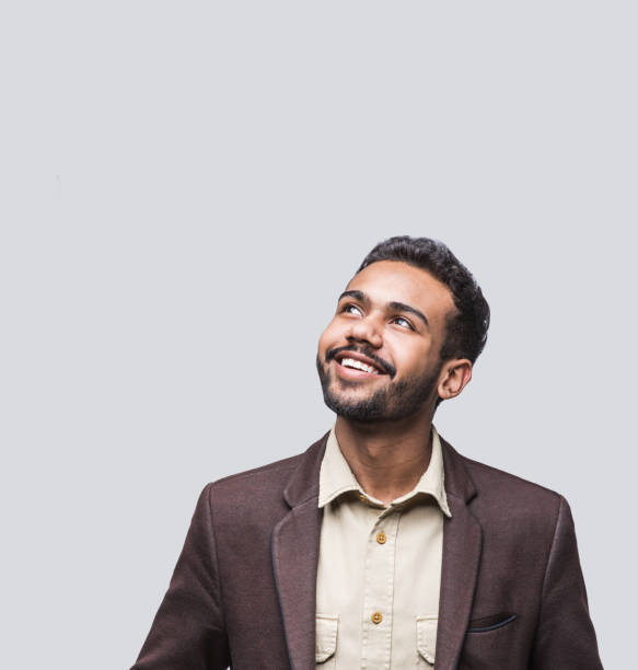 Portrait of handsome smiling young man looking up Cheerful young men looking up. Isolated on gray background looking up stock pictures, royalty-free photos & images