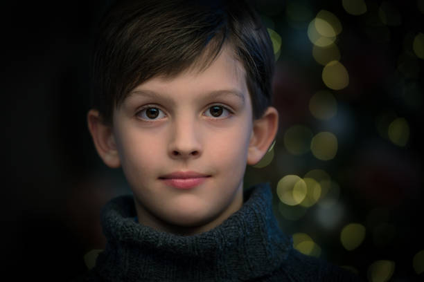 Portrait of happy boy infront of christmas tree blur light stock photo