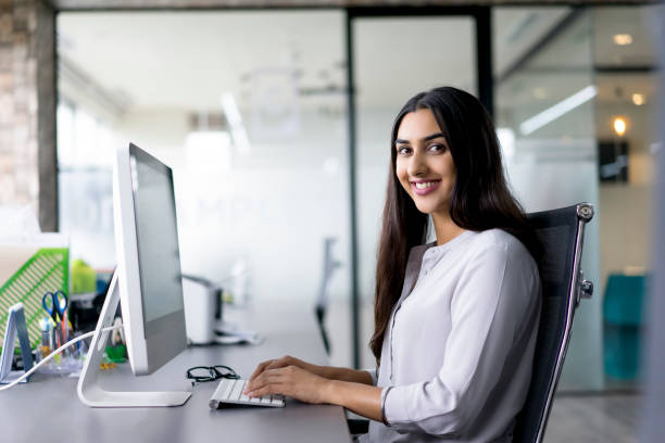 Portrait of happy female employee at computer stock photo