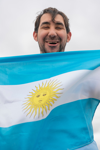 Portrait of a mentally disabled fan upraroiusly celebrating and chanting with argentina flag during soccer competition