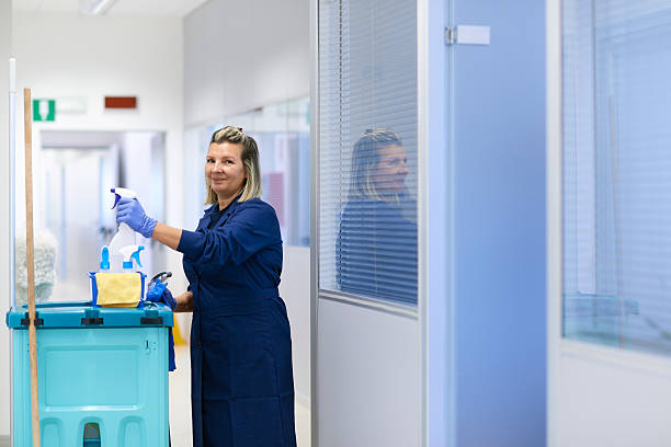 Portrait of happy professional female cleaner smiling in office stock photo