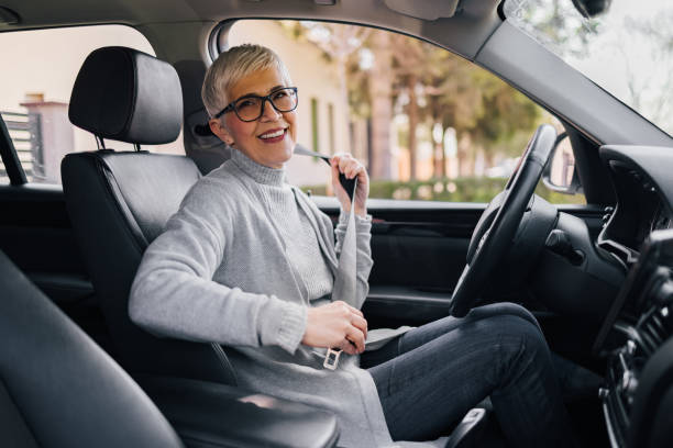 Portrait of happy senior woman fastening seat belt before driving a car. stock photo